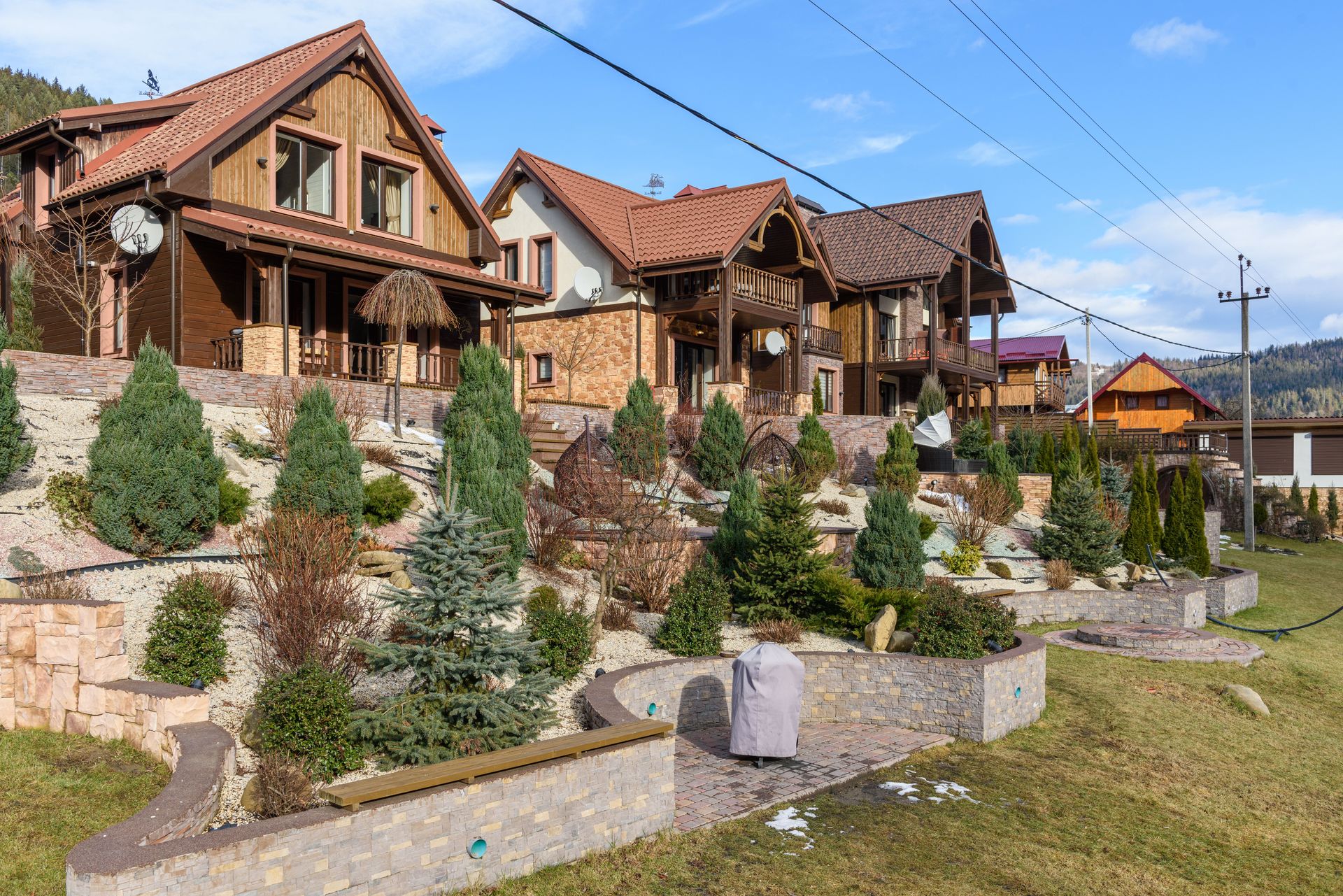 Rustic houses with sloped roofs and landscaped gardens under clear blue skies. Ideal for real estate visuals.